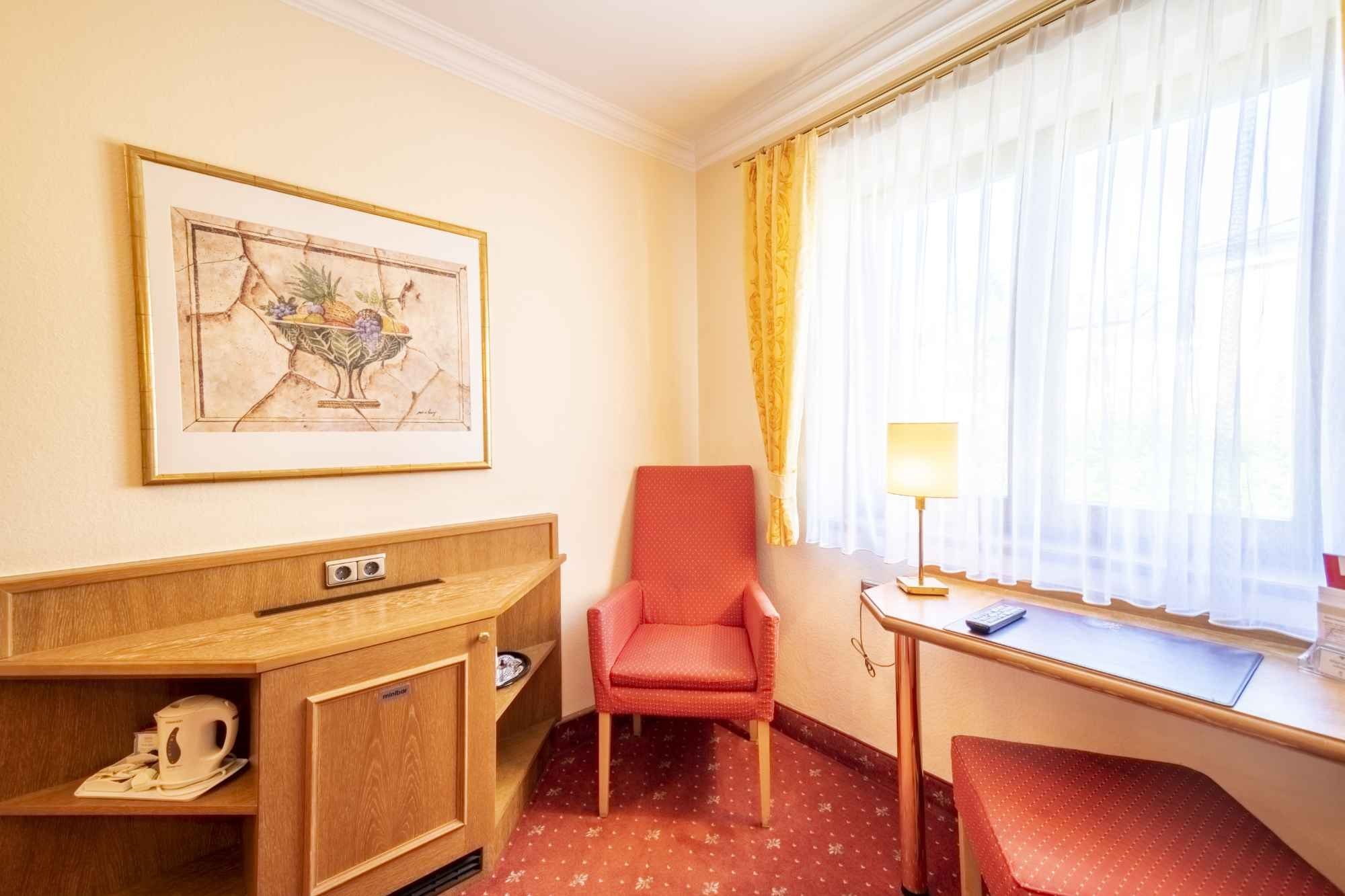 Hotelzimmer mit rotem Sessel am Fenster